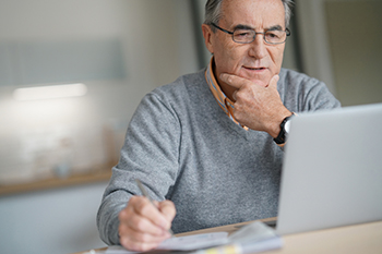 Older man reading a laptop