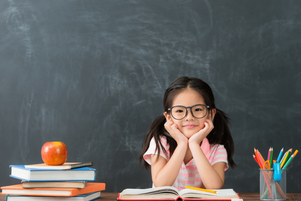 child sitting with school books and chalkboard