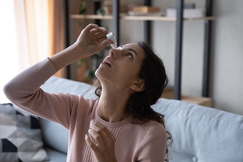 Woman Putting eyedrops into her eye